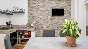 Una cocina compacta con protector de piedra, una televisión de pantalla plana y un comedor con mesa y sillas.