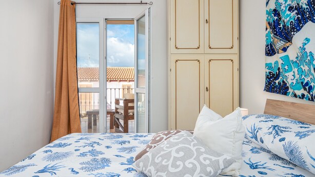 Un dormitorio con cama, armario y vistas al exterior.