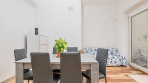 Un comedor con una mesa, sillas, una planta en maceta y un sofá con estampado.