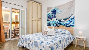 Un dormitorio con cama, mesita de noche, tapiz y vistas a un balcón exterior.