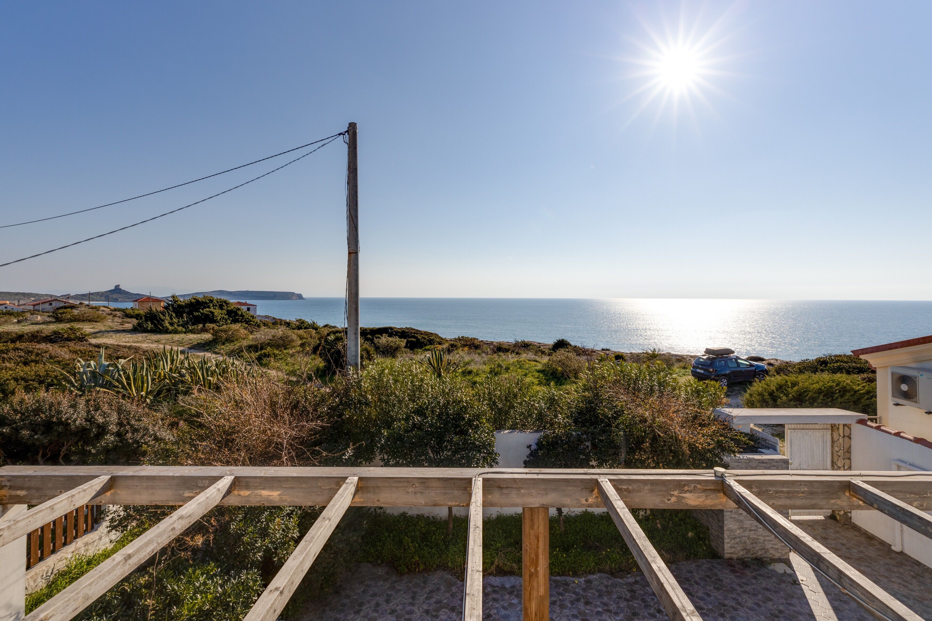 A coastal view with a wooden deck, a utility pole, and a distant body of water.