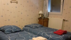 A bedroom with two beds, a nightstand, a lamp, and a window. - Fully-equipped Meublé de Tourisme for rent, sleeps 6 (Discounts + nights) (nanchez)