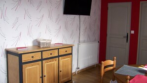 A room with a wooden cabinet, a television mounted on the wall, a radiator, and a door. - Fully-equipped Meublé de Tourisme for rent, sleeps 6 (Discounts + nights) (nanchez)