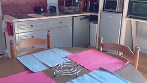 A compact kitchen with a dining table set for four, a microwave, a refrigerator, and a sink. - Fully-equipped Meublé de Tourisme for rent, sleeps 6 (Discounts + nights) (nanchez)