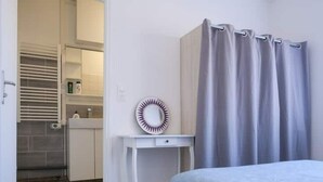 A bedroom with a bed, a small bedside table, a mirror, and a bathroom with a shower curtain. - Les Chevalets Iv/stade Bollaert/louvre/université (Lens)