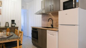 A compact kitchen with a refrigerator, microwave, stove, and sink. There is a dining table with chairs and a coffee maker on the counter. - Les Chevalets Iv/stade Bollaert/louvre/université (Lens)