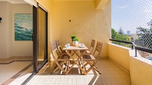 Ein Balkon mit Tisch, Stühlen, einer Zimmerpflanze und einem Bild an der Wand.