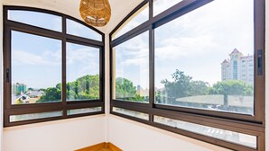 Ein Zimmer mit großen Fenstern, Holzboden und einer Deckenleuchte.