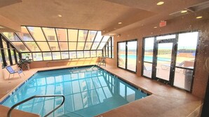 An indoor swimming pool with clear glass walls, a pool ladder, and a view of the outside. - Private Fishing Pier! (Orange Beach)