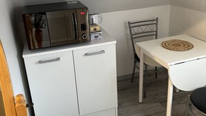Une petite cuisine équipée d’un four à micro-ondes, d’une machine à café et d’un petit placard.
