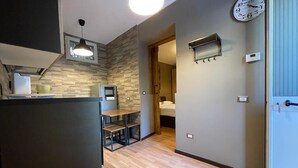 Une cuisine moderne dotée d’une cuisinière intégrée, un coin repas avec une table et des chaises, une horloge au mur et une porte donnant sur une autre pièce.