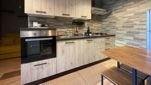 Une cuisine moderne avec des meubles en bois, un four encastré et un coin repas comprenant une table et un banc en bois.