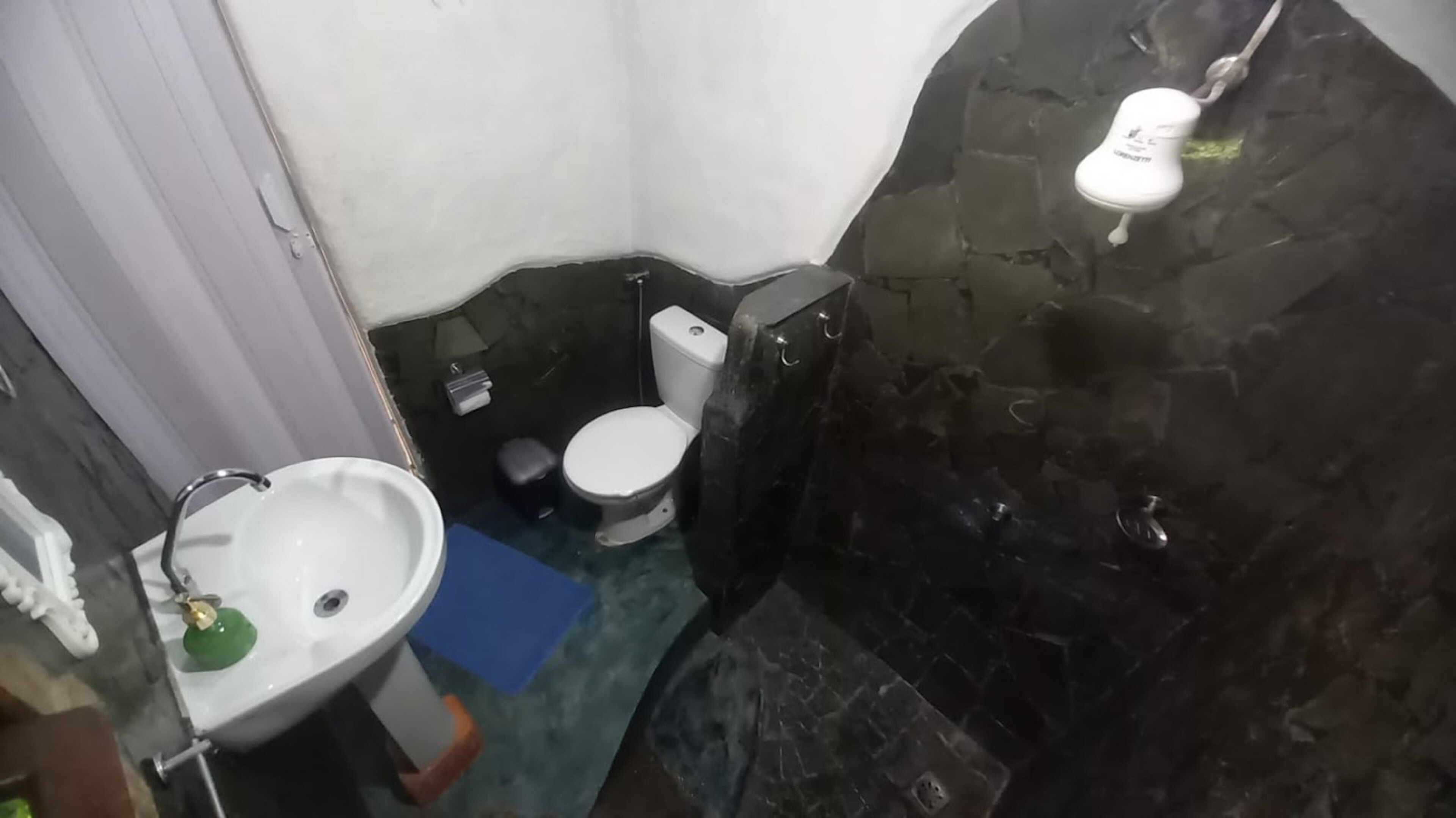 A small bathroom with a white sink, a toilet, and a shower area.