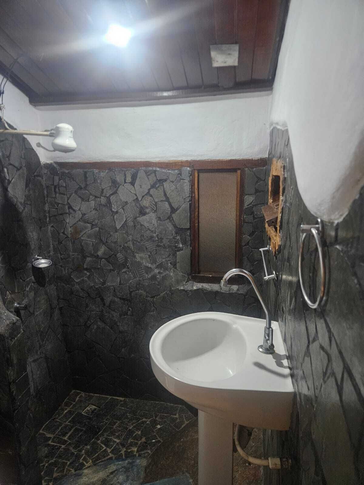 A bathroom with a stone wall, a white sink, and a shower area.