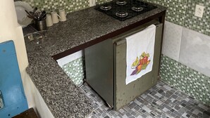 Una cocina compacta con estufa a gas, un lavamanos y un salpicadero de azulejos.