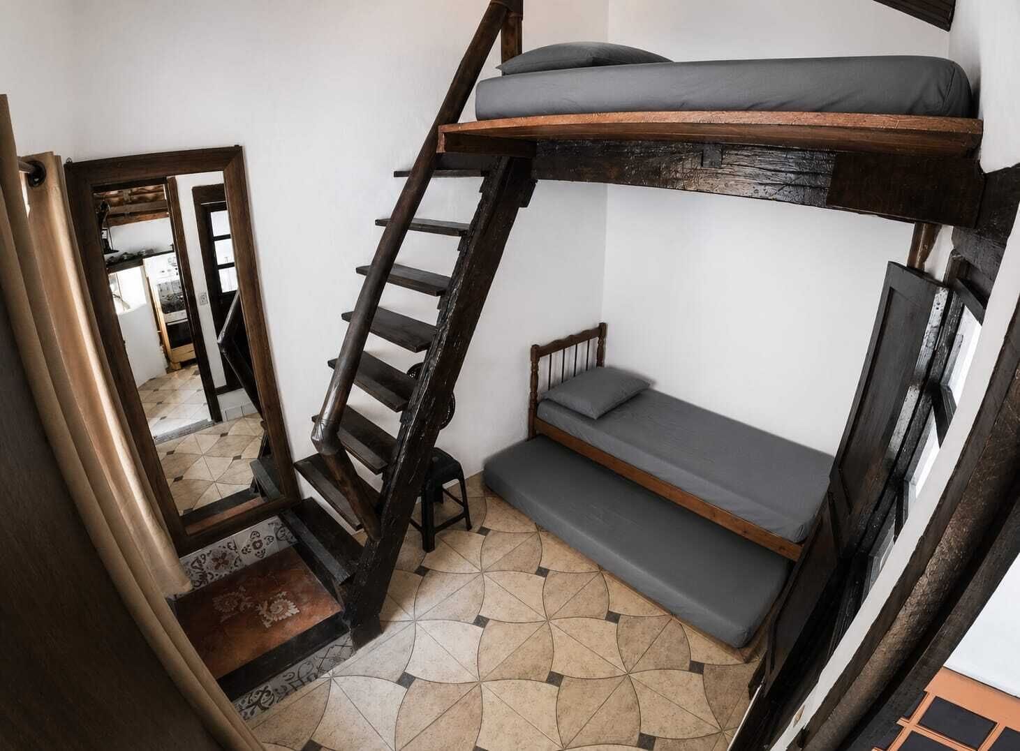 A bunk bed with a ladder, a small seating area, and a patterned floor.