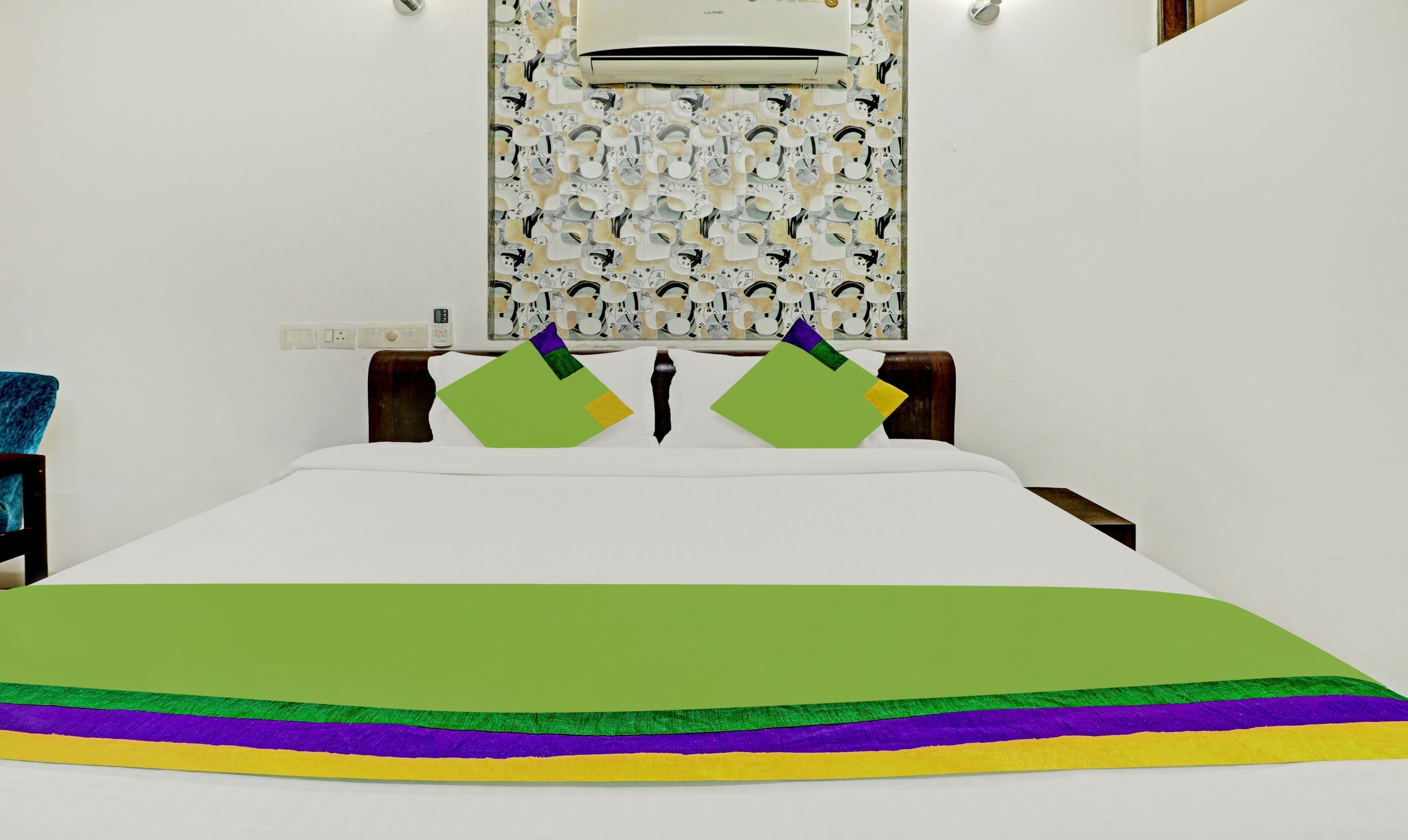Habitación de hotel con una cama, aire acondicionado instalado en la pared y un papel tapiz estampado.