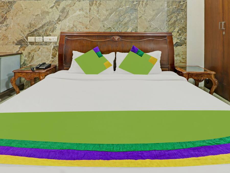 A hotel room with a bed, a wooden headboard, a nightstand, a telephone, and a wardrobe.