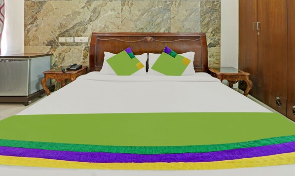 A hotel room with a bed, a wooden headboard, a nightstand, a telephone, and a wardrobe.