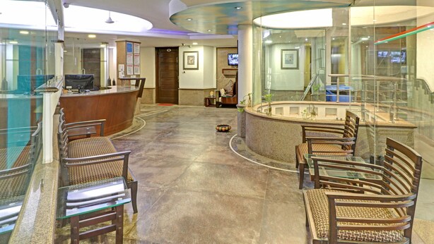A lobby with a reception desk, seating area, and a glass railing overlooking a lower level. - Treebo Sky 5 (Panchkula)