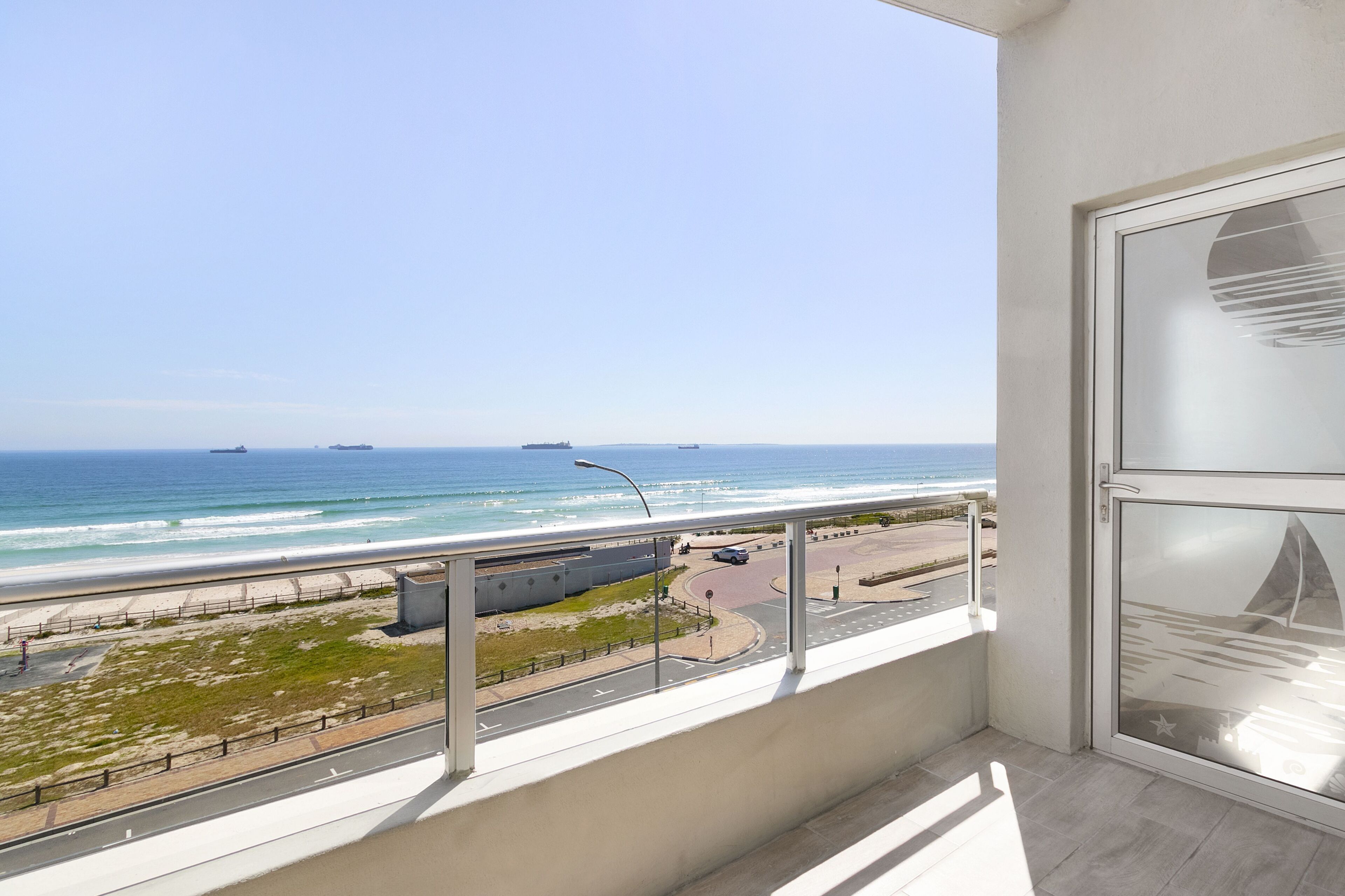 A balcony with a view of the beach and ocean.