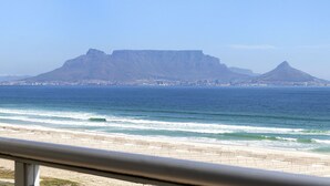 Ein Küstenblick mit einem markanten Berg im Hintergrund und einem Strand im Vordergrund.