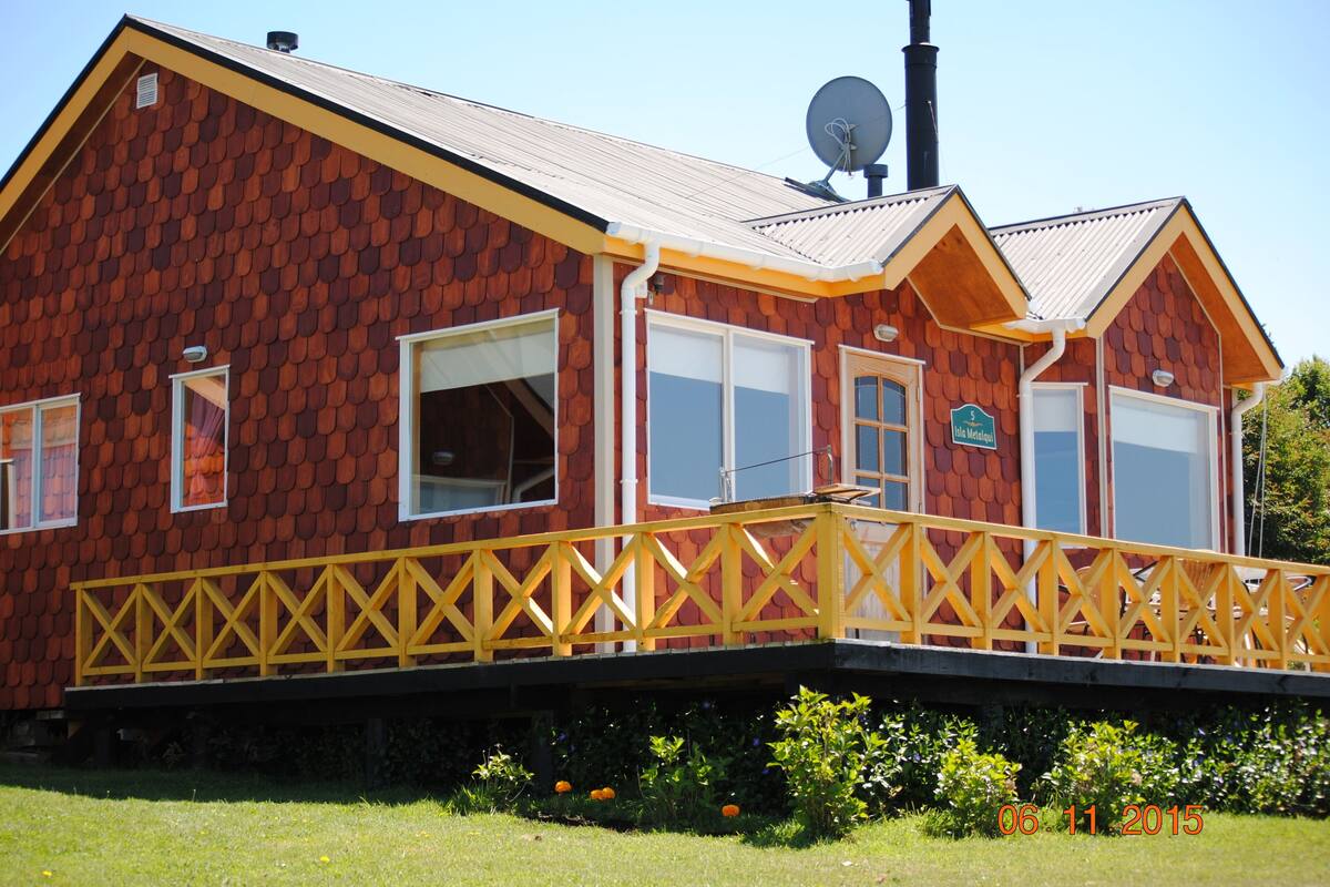 A two-story building with a red exterior, yellow trim, and a balcony with a yellow railing.