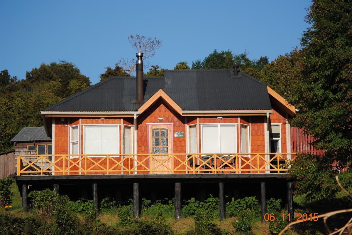 A two-story house with a balcony, a chimney, and a date stamp.