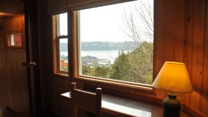 A wooden room with a large window overlooking a lake and trees. - Cabañas Trayen Chiloé (Castro)