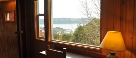 A wooden room with a large window overlooking a lake and trees.