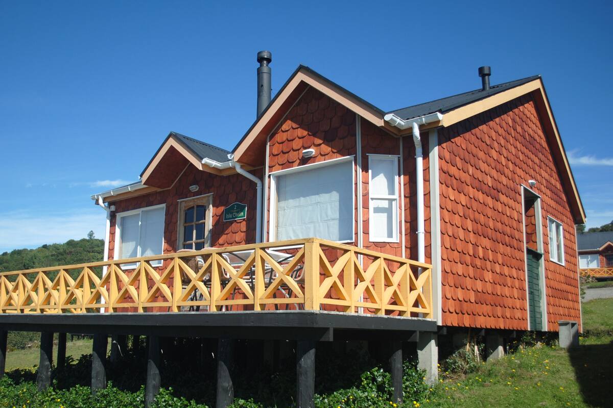A wooden house with a balcony, a chimney, and a sign that reads "2 Isla Cheiln".