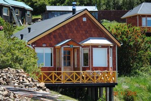 Una cabaña de madera con balcón, una puerta y una ventana.