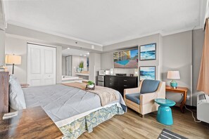 Una habitación de hotel con cama, sillón, mesita, televisor, escritorio y armario.