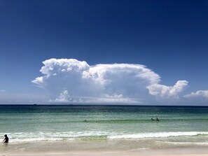 A beach with clear skies and a large cloud formation.