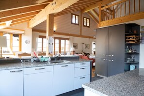 Eine geräumige Küche mit Granit-Arbeitsplatten, weißen Schränken und einer Holzbalkendecke.