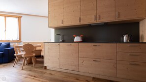 A compact kitchen with wooden cabinets, a black countertop, and a toaster. - Italianway - Castellazzi 12 Aquila (Bormio)