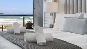 A hotel room with a bed, a view of the ocean, and a lamp.