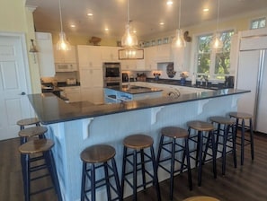 Una cocina moderna con una isla central, taburetes de bar e iluminación colgante.