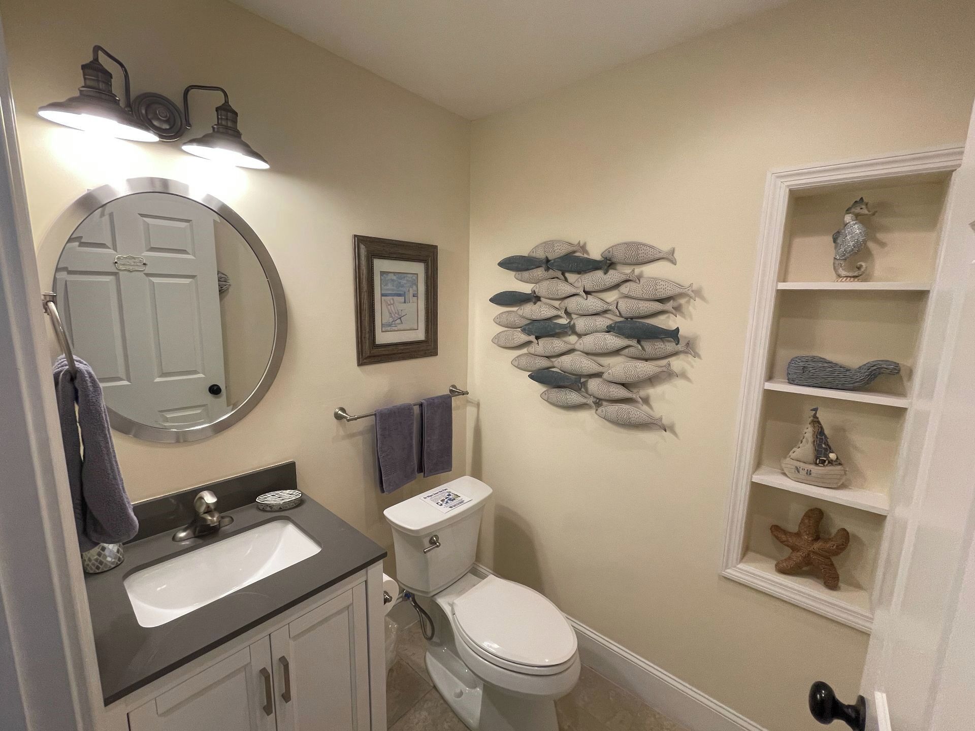 A bathroom with a sink, toilet, and a decorative fish wall art.