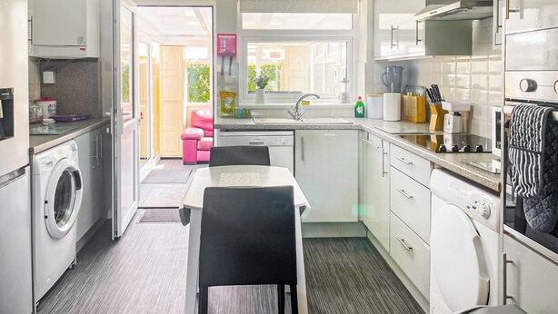 A compact kitchen with a washing machine, a dining table, and a sink.