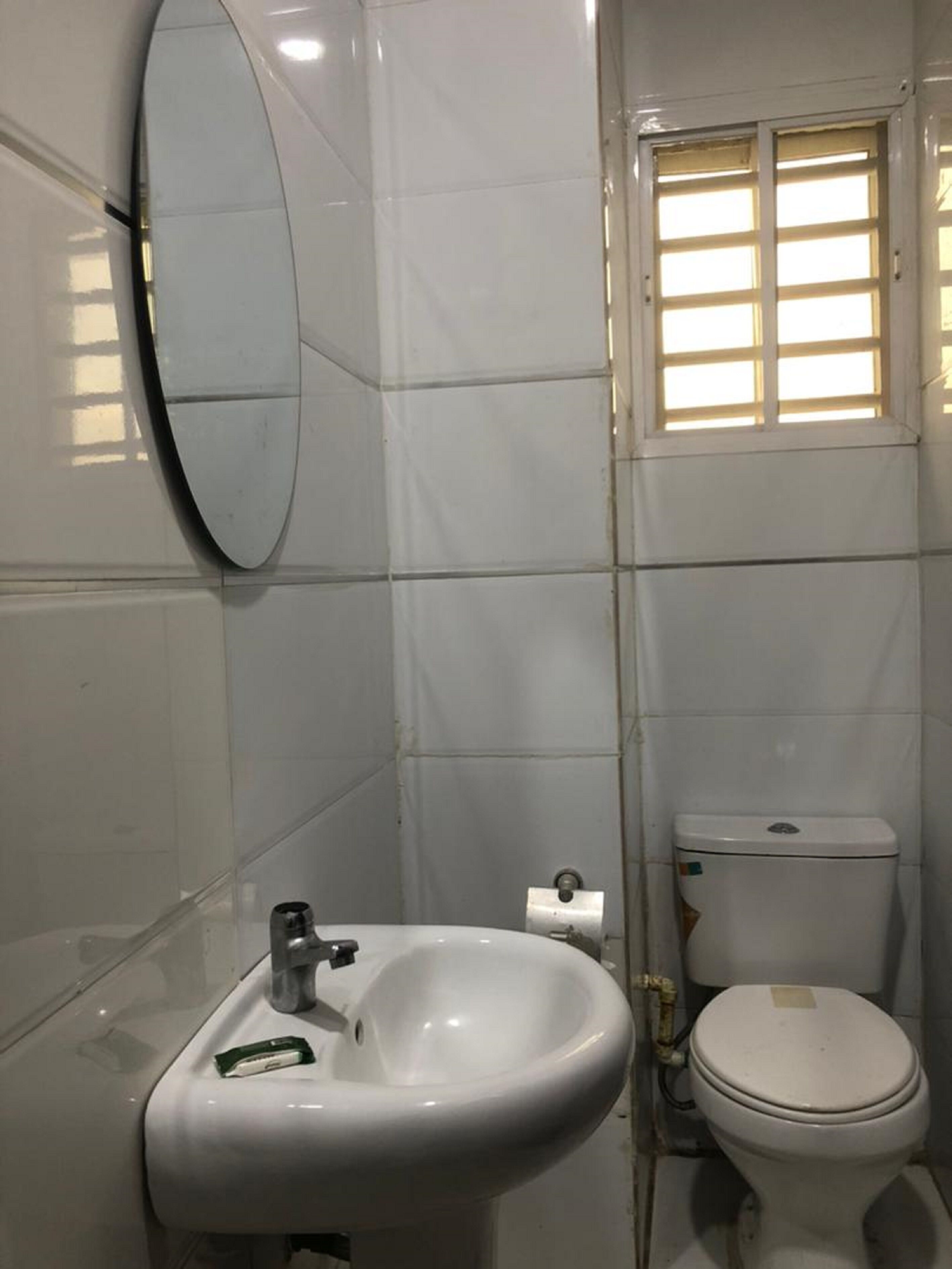 A bathroom with a white sink, mirror, and toilet.