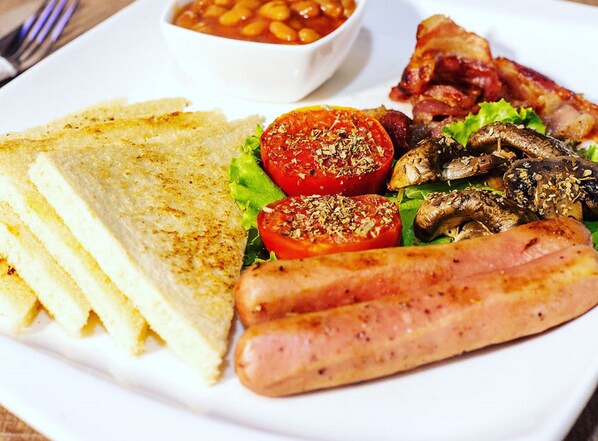 A plate with grilled sausages, tomatoes, mushrooms, lettuce, and toast.
