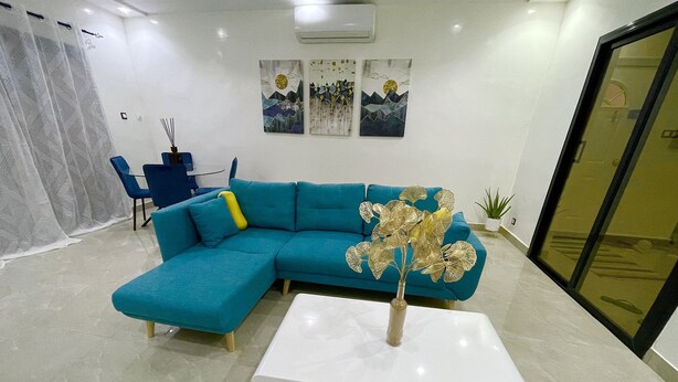 Una sala de estar moderna con un sofá seccional color turquesa, una mesa de centro blanca y decoración de pared.
