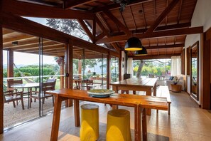 A spacious indoor area with wooden beams and large windows, offering views of greenery and a distant landscape. - Magnificent views, 3 suites, pool w/ heated tub (Petrópolis)