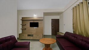 A modern living room with a wooden entertainment unit, a round wooden coffee table, and two leather sofas. - Treebo SLN Heritage (Bengaluru)