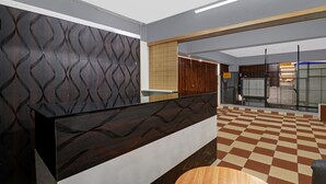 A reception area with a modern design, featuring a patterned wall, a reception desk, and a checkered floor. - Treebo SLN Heritage (Bengaluru)
