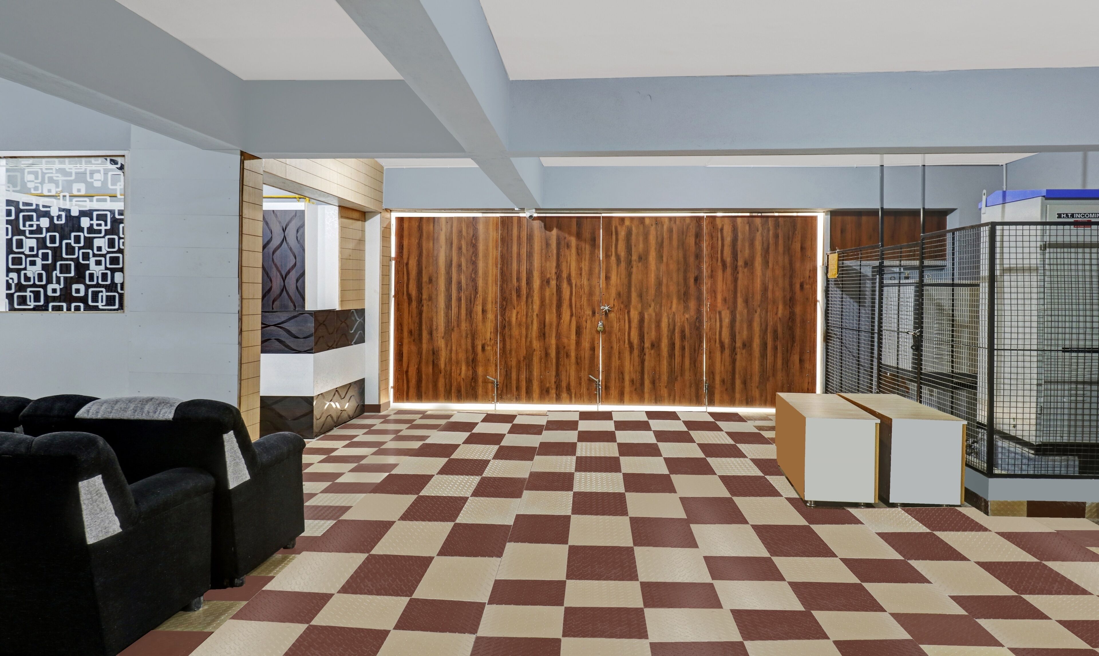 A hotel lobby with a checkered floor, a wooden partition with a door, and a cage-like structure on the right.