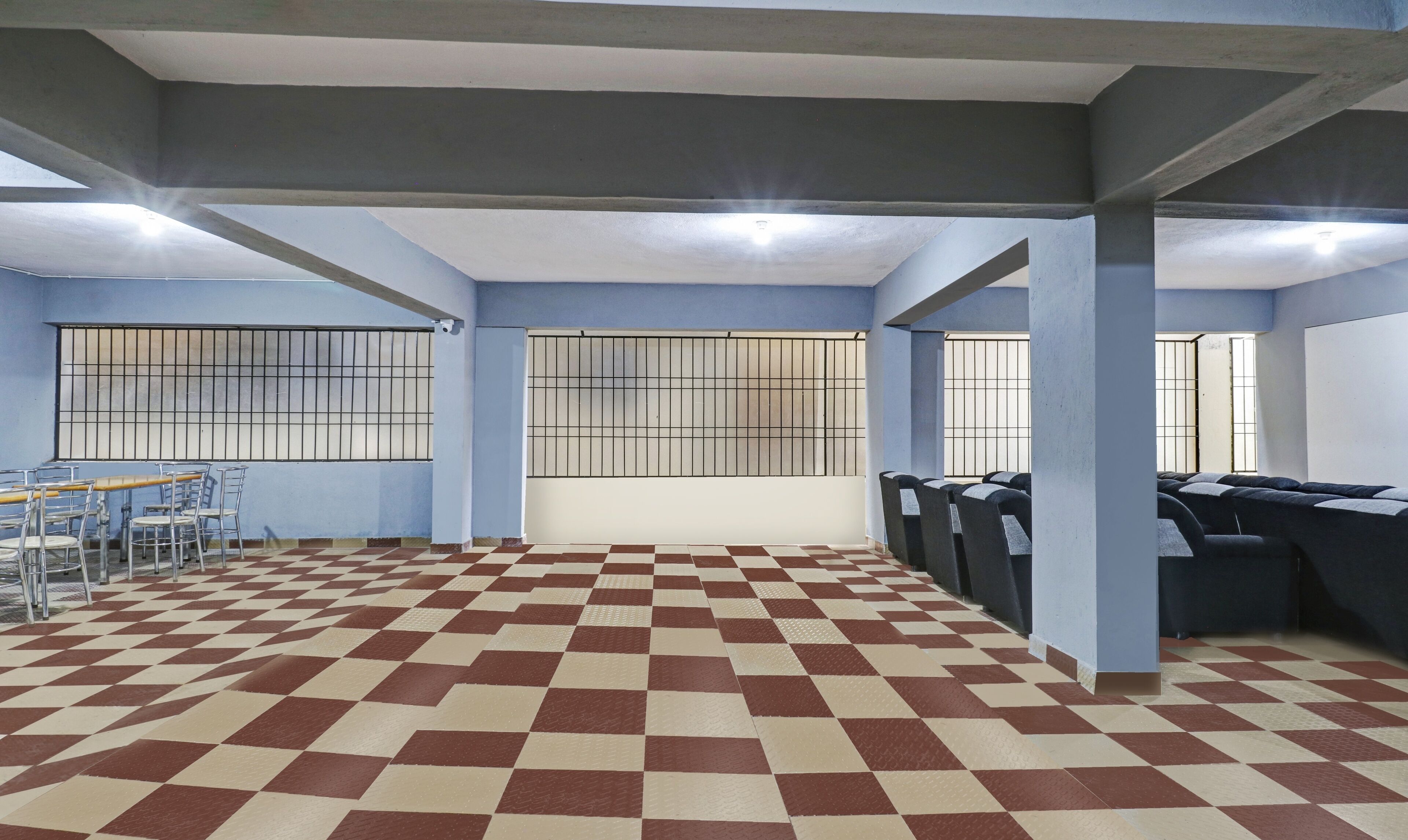 A room with a checkered floor, metal chairs, a table, and barred windows.