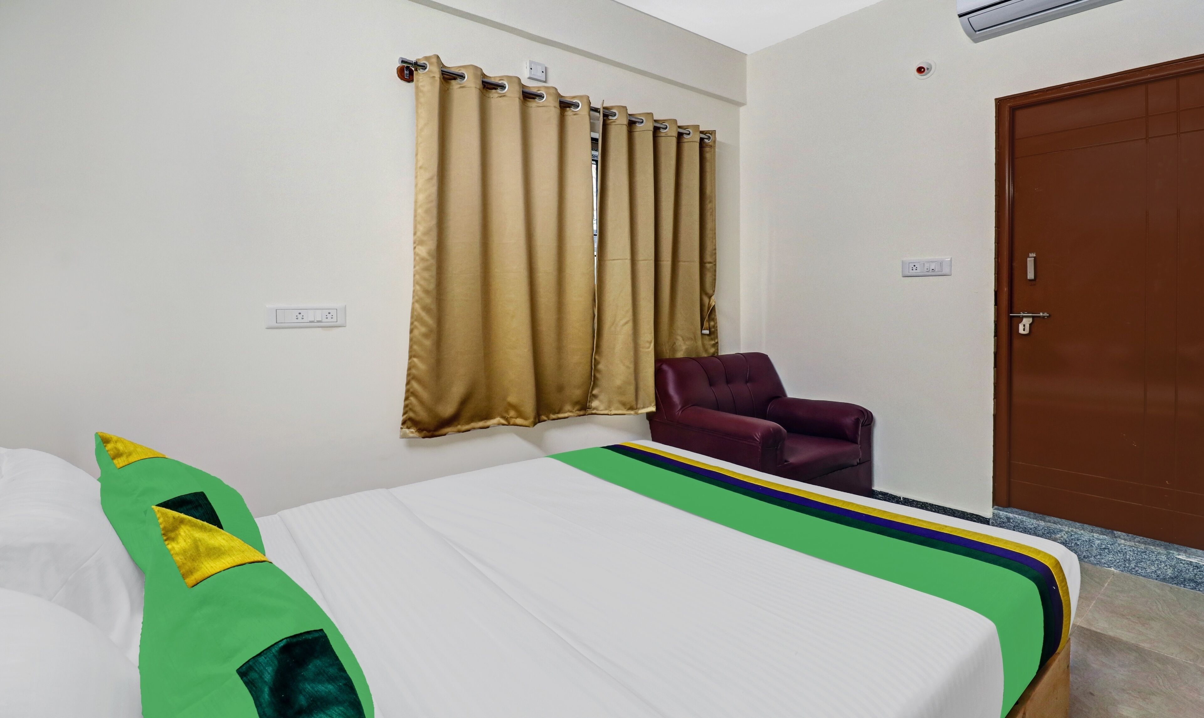 Une chambre d’hôtel avec un lit, une chaise, une porte et une fenêtre avec des rideaux.