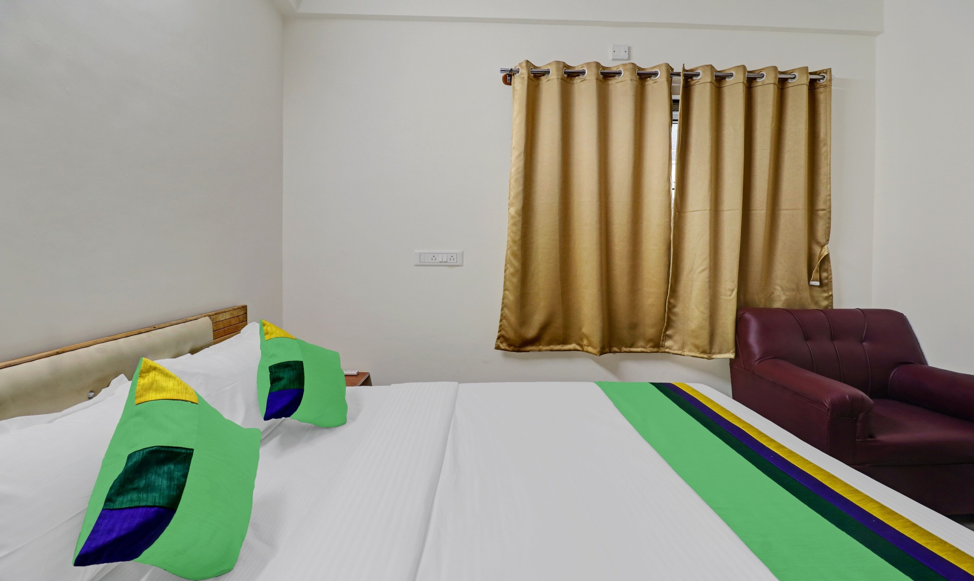 A hotel room with a bed, a chair, and a window with curtains.